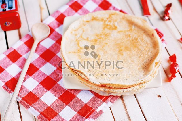 Pancakes and wooden spoon on checkered dishcloth - image gratuit #136447 