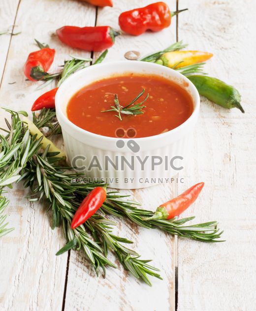 tomato sauce with rosemary and chili peppers on a wooden table - image #183367 gratis