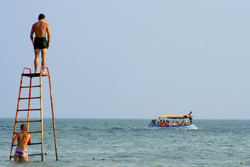 Guys on iron tower and tourists in boat - бесплатный image #187777
