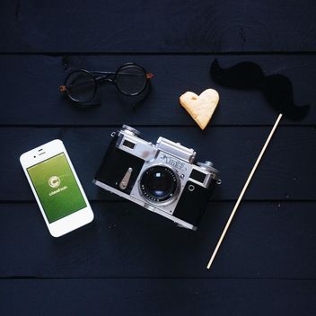 Smartphone with Clashot logo, retro camera and accessories on dark wooden background - бесплатный image #329307