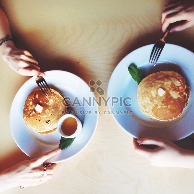 Hands of couple eating pancakes for breakfast - image #345027 gratis