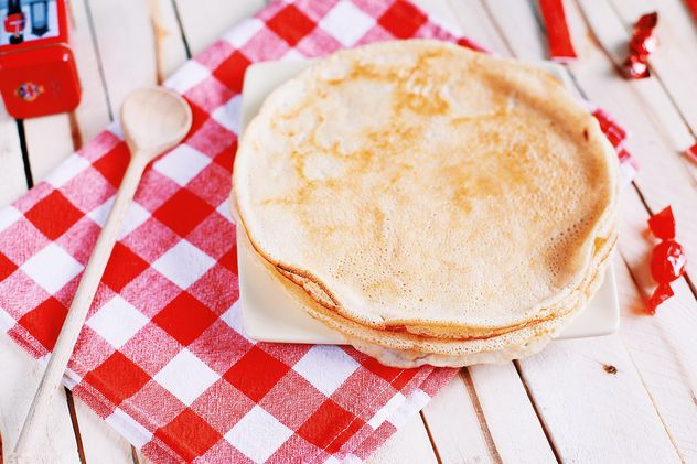 Pancakes and wooden spoon on checkered dishcloth - image #136447 gratis
