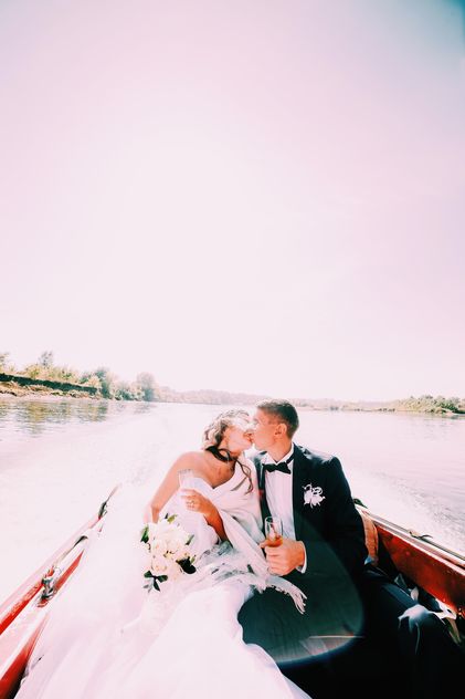 Happy wedding couple in boat on lake - image #184097 gratis
