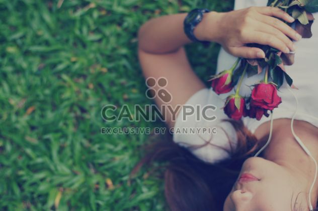 Girl with roses laying on grass - image #198087 gratis