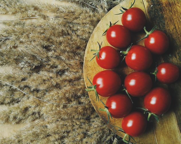 Tomatoes on wooden board on dry spicas - Free image #274857