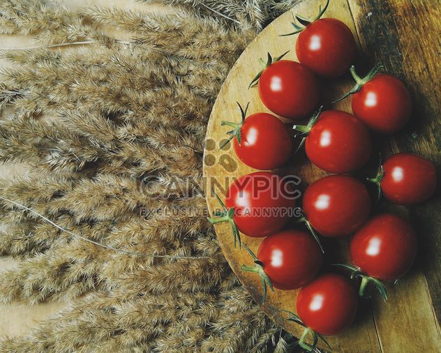 Tomatoes on wooden board on dry spicas - Free image #274857