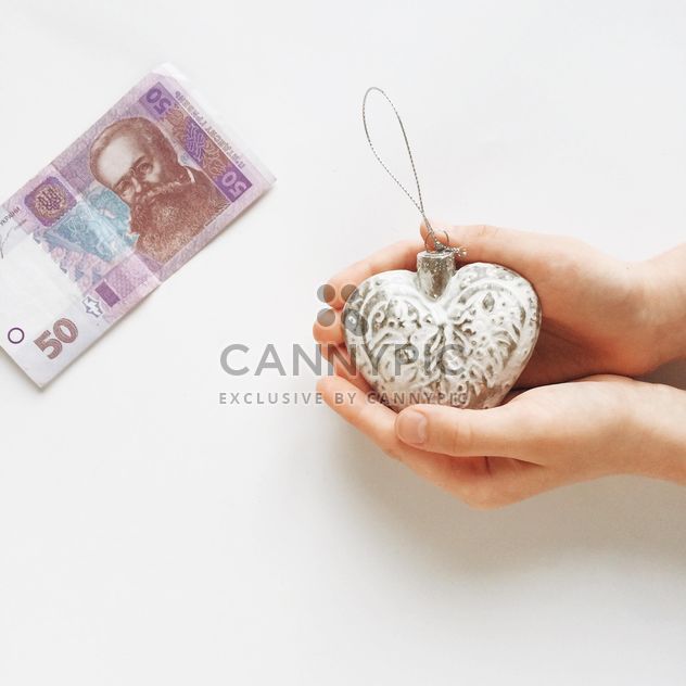 Woman's hands holding christmas toy and money on the white table - бесплатный image #329237