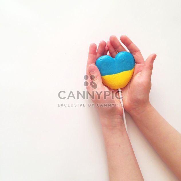 Hands holding lollipop in colors of Ukrainian flag on white background - Kostenloses image #329297
