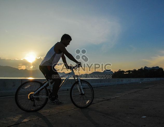Man riding a bicycle down the road - бесплатный image #330357