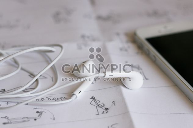 Closeup of smartphone and earphones on paper - image #345047 gratis