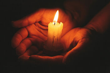 Female hands and candle flame close up on black background - image #474697 gratis