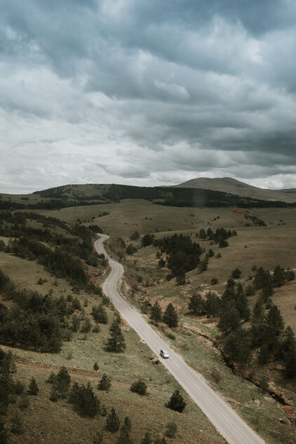 Road on a cloudy day disappearing into the horizon among the green mountains. - image #480547 gratis